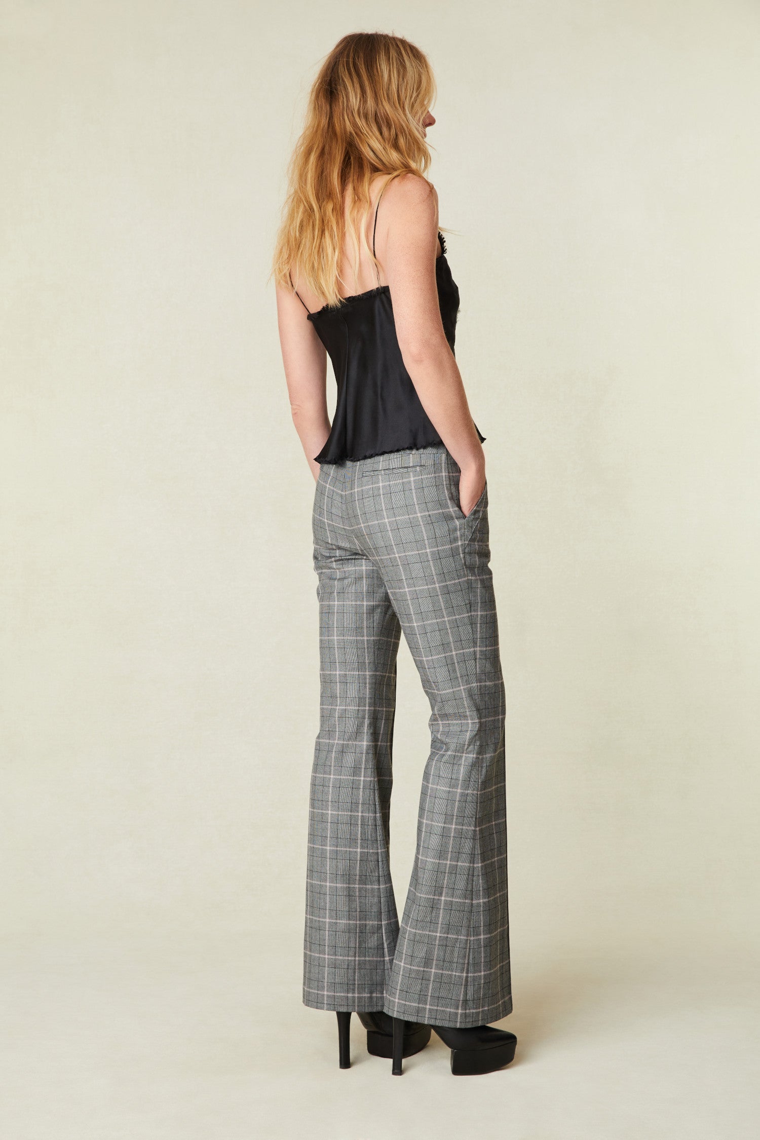 low rise, plaid pants have a flare fit and feature tabs on each side with enameled buttons, a pintuck detail going down center front, a pocket in the back, top stitch pockets on the front, and a fly zipper with hook and bar closure.  