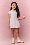 Young girl wearing a white t-shirt dress against a pink background