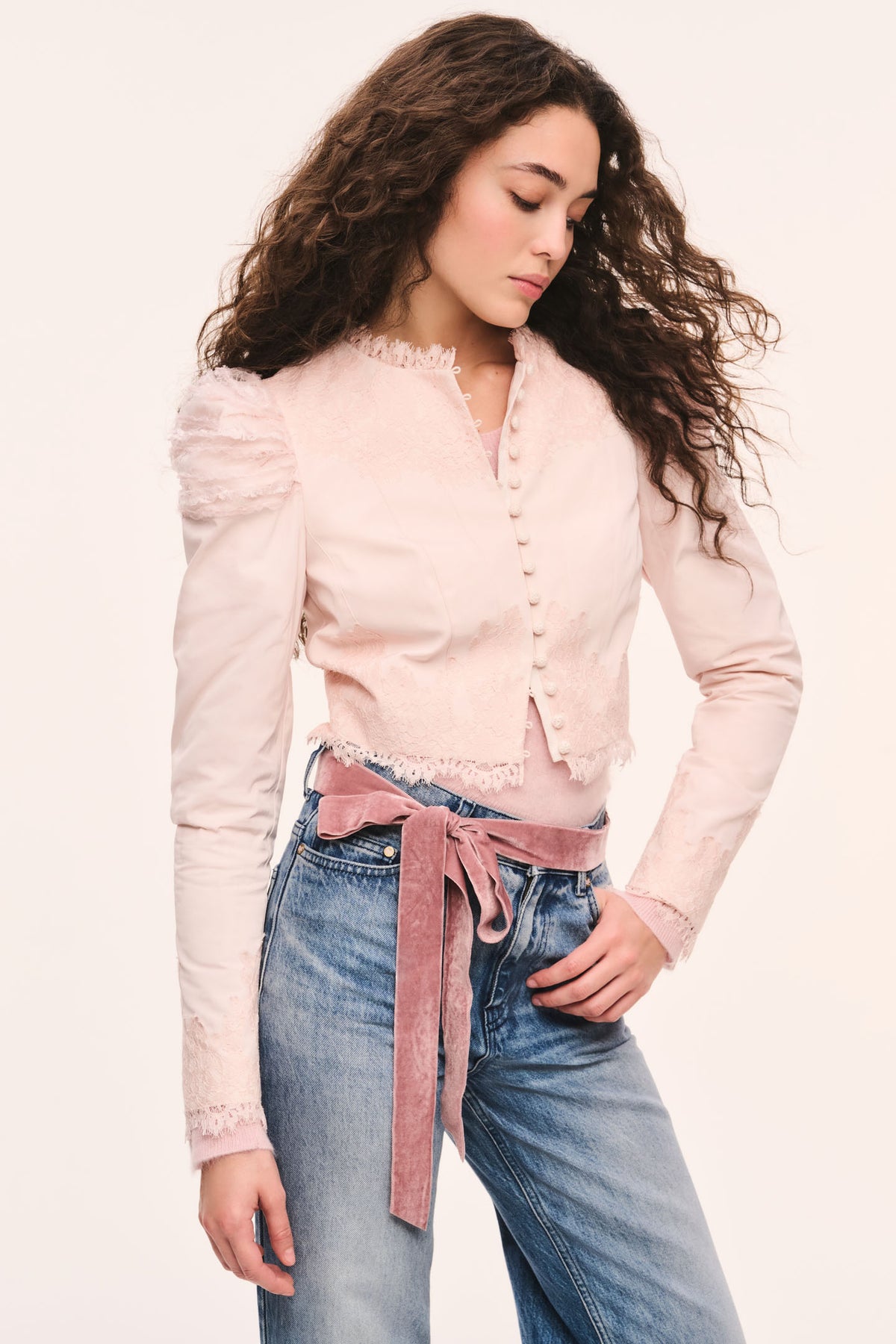 Light pink cropped jacket front view with button placket, puff sleeves, and lace-trim ruffle edges styled over a pink sweater