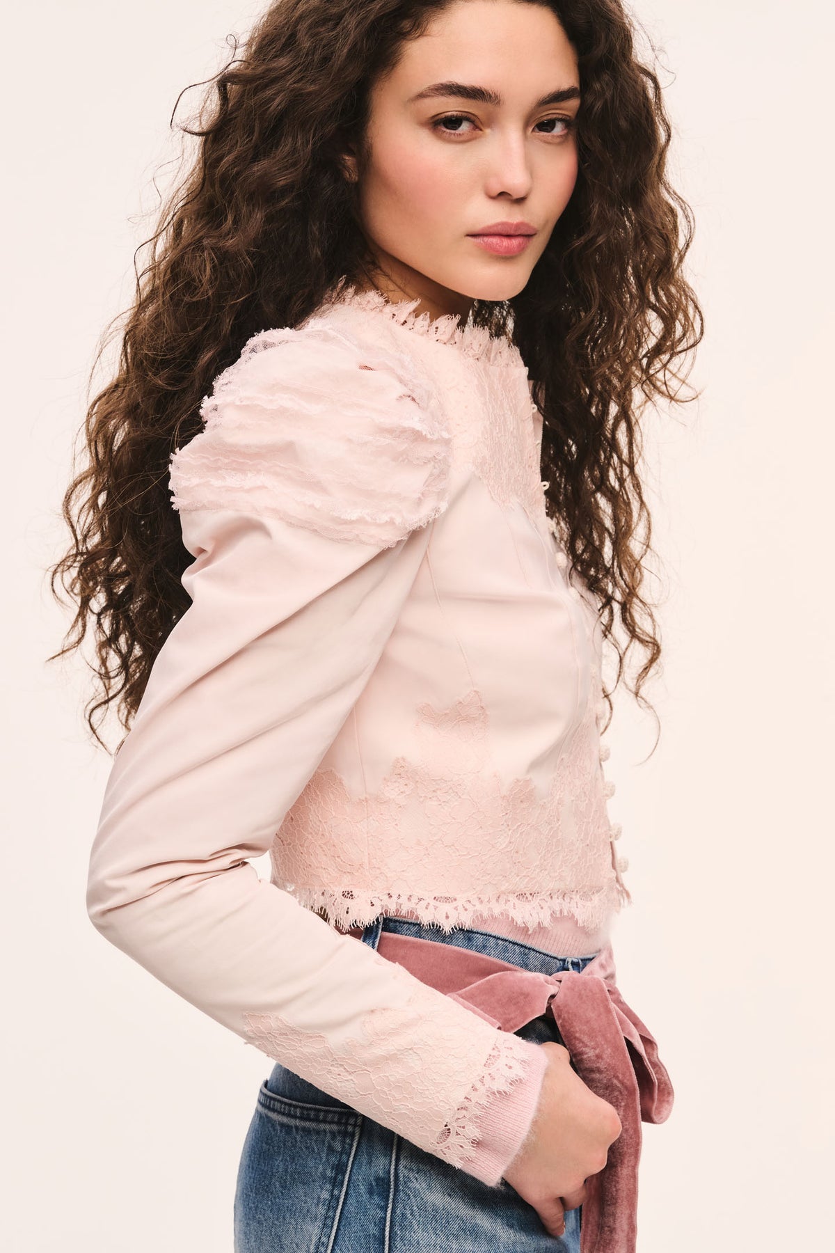 Light pink cropped jacket side view with button placket, puff sleeves, and lace-trim ruffle edges