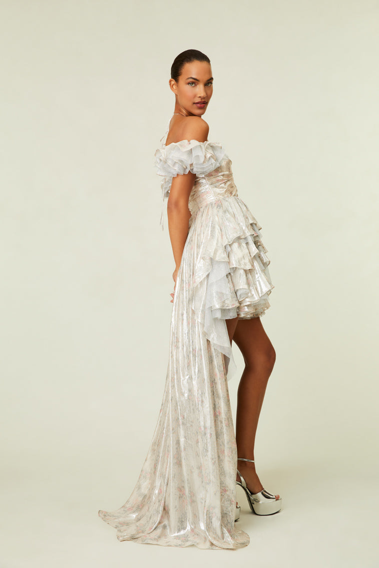 The dress features a high-to-low silhouette with a halter neckline descending to multi-tiered ruffles all over.