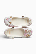Pair of white rubber shoes with floral decorations on a white background