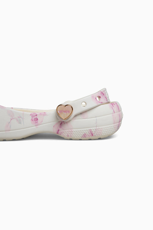 White shoe with pink floral pattern and gold heart charm on a white background