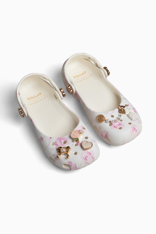 Pair of rubber shoes with floral patterns and embellishments on a white background