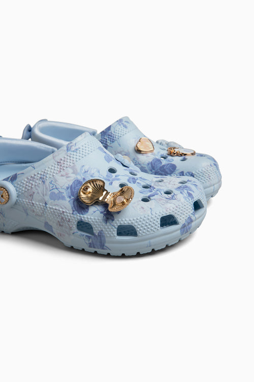 Pair of light blue croc clogs sandals with floral patterns on a white background