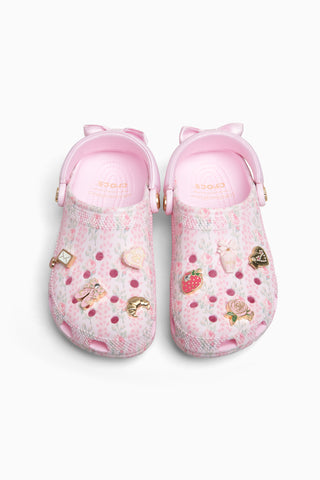 Pink rubber clogs with decorative charms on a white background