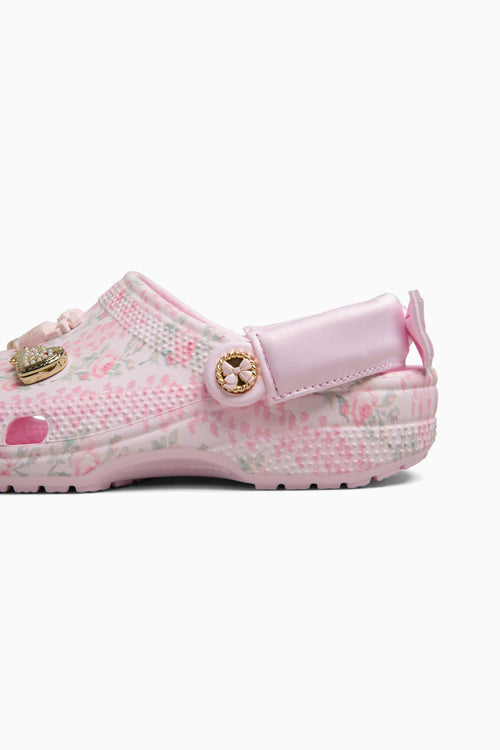 Pink croc shoe with decorative elements on a white background