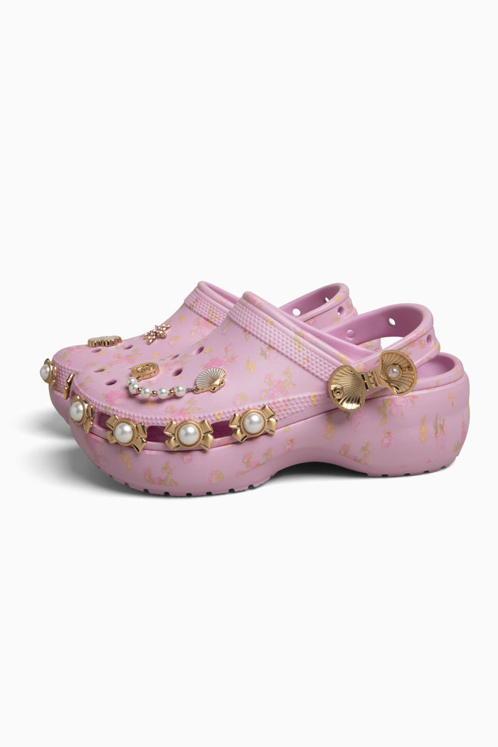 Pink rubber clogs with embellishments on a white background