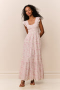 Woman wearing a maxi floral dress against a plain background