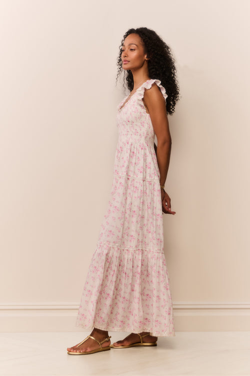 Woman wearing a maxi floral dress against a plain background