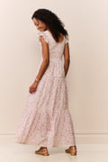 Woman wearing a maxi floral dress against a plain background
