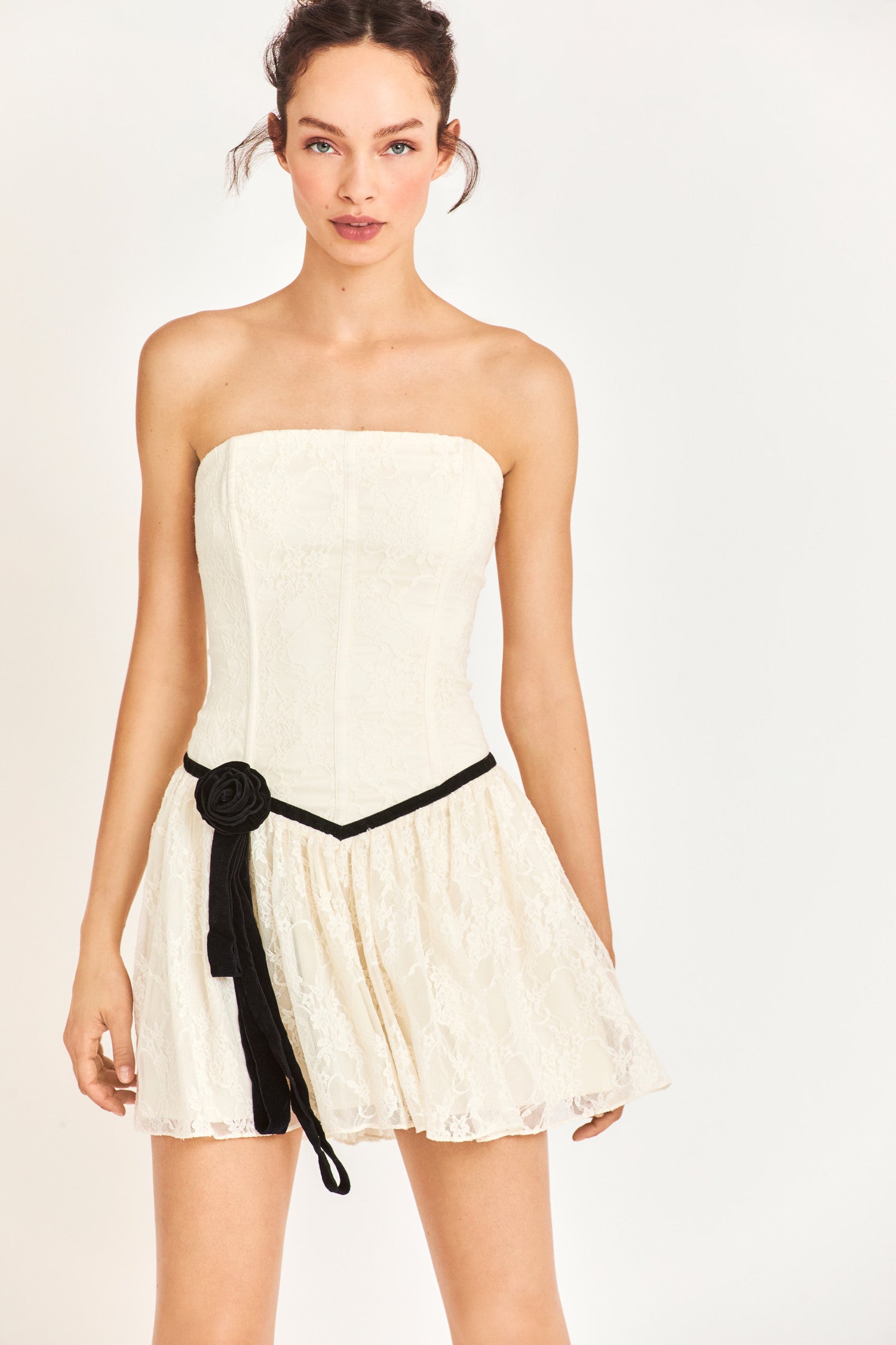 Model wearing white mini dress with black flower detail