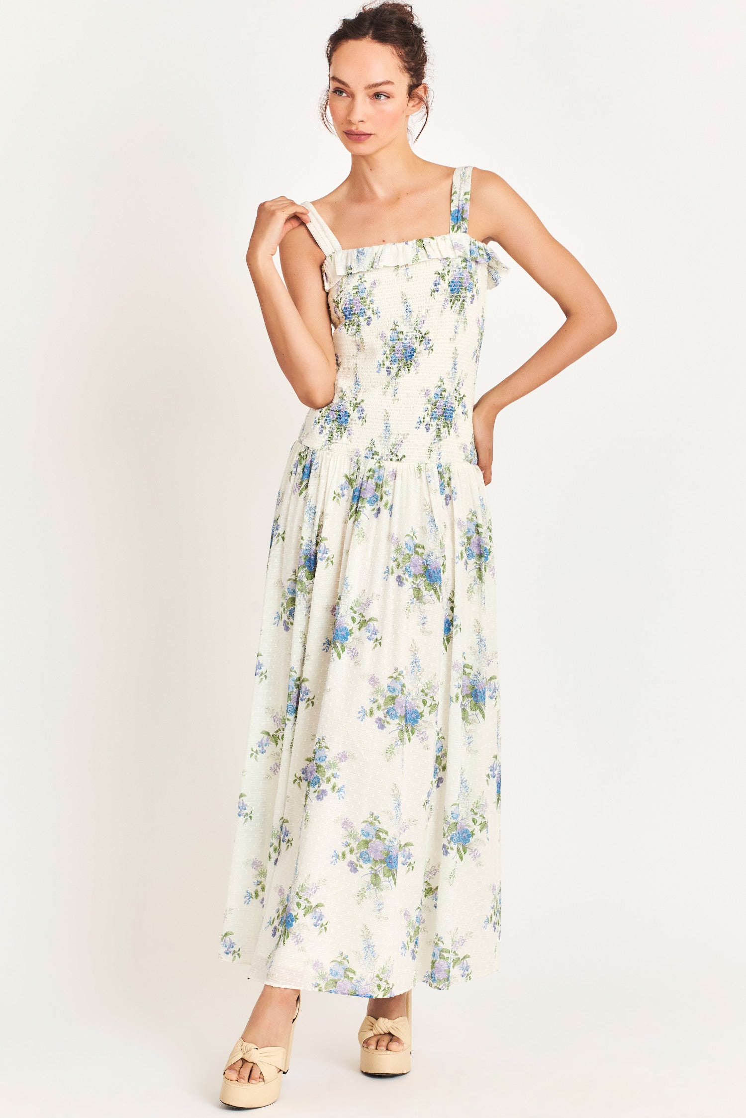White Maxi dress with a blue heirloom bouquet print on a soft textured dot cotton fabric and a smocked bodice that releases into a sweeping A-line skirt. 