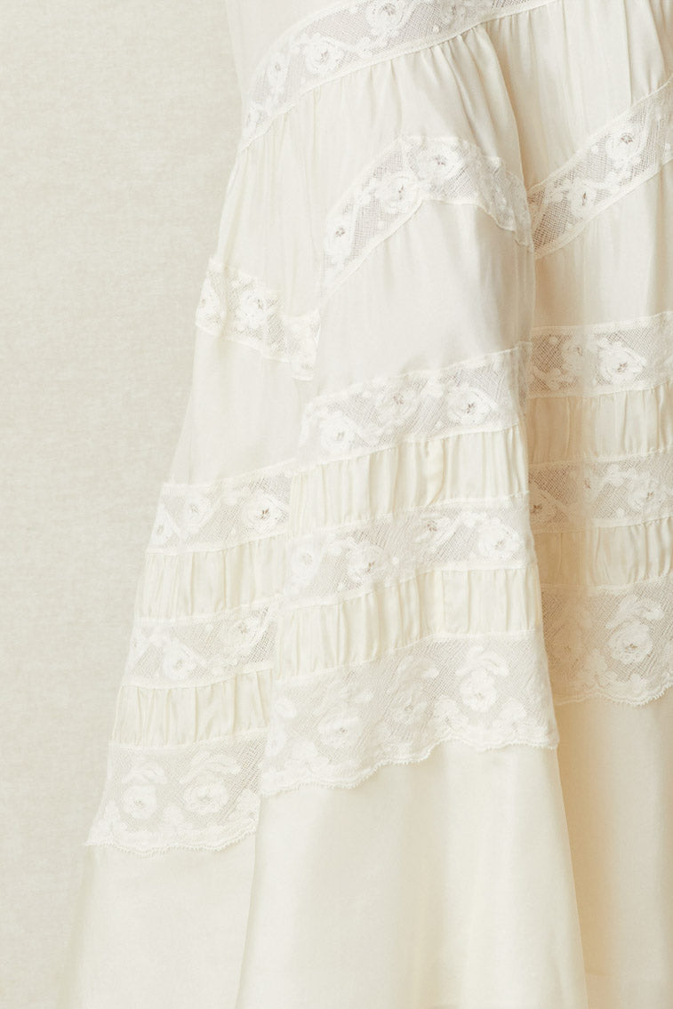 Close up image detailing lace on white silk maxi dress