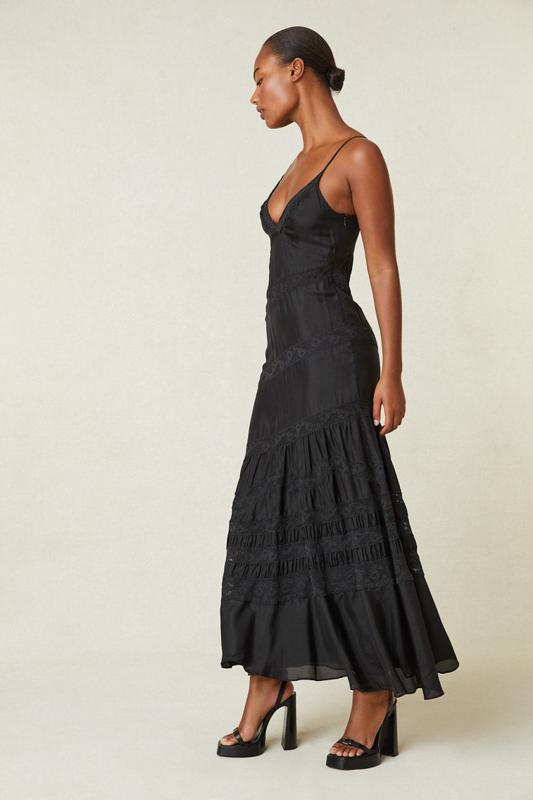 Side image of model wearing black maxi silk dress with lace detail