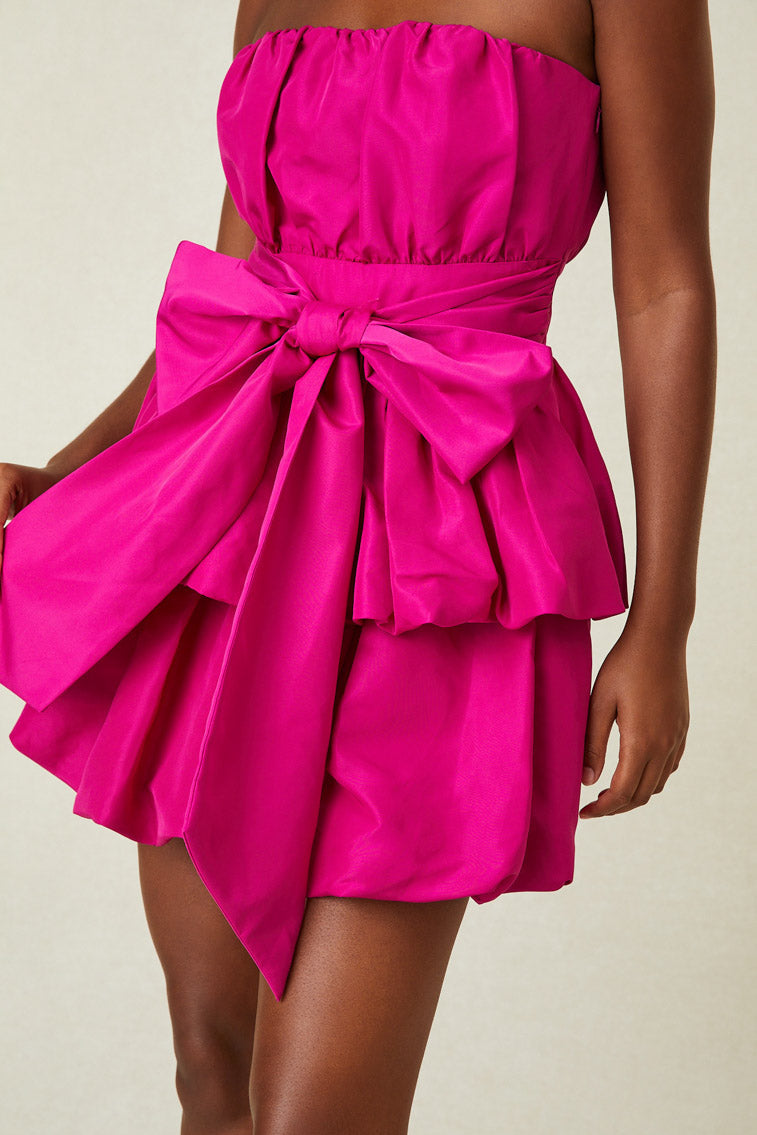 Model wearing pink strapless mini dress with low detail at waist