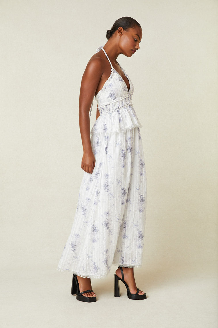 Side image of model wearing white and purple floral halter dress