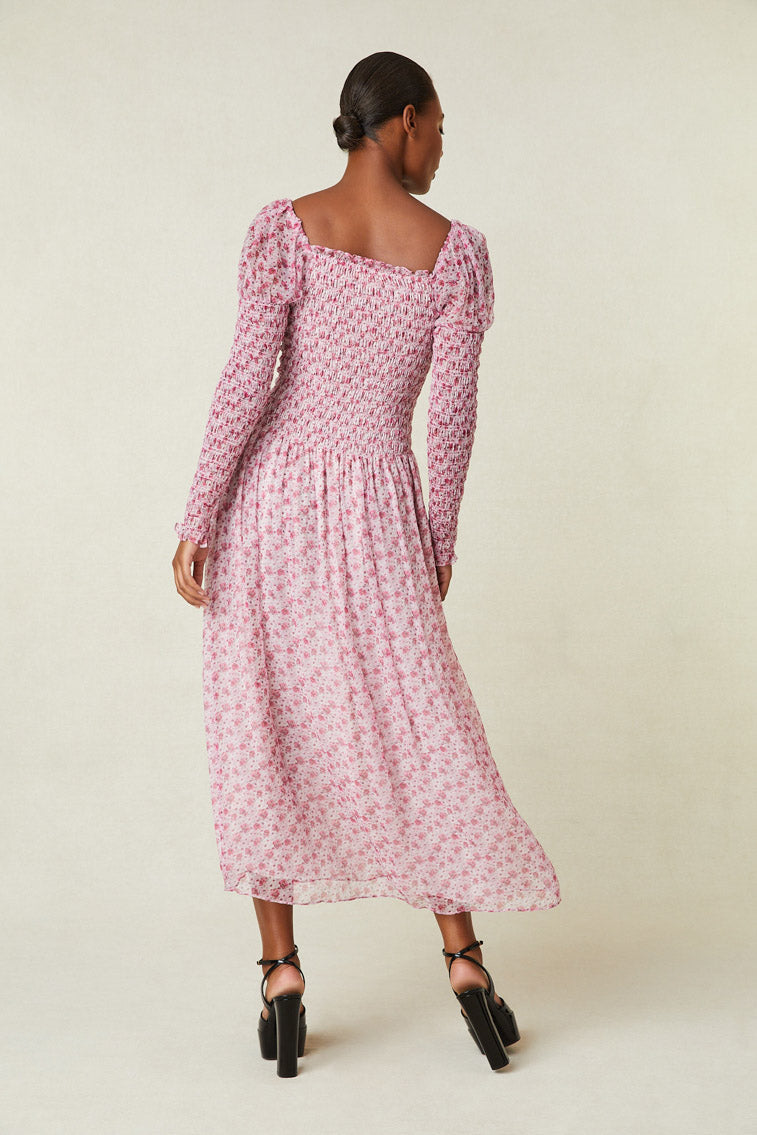 Back image of model wearing pink floral maxi dress with smocked top, puffed shoulders, and an a-line skirt.