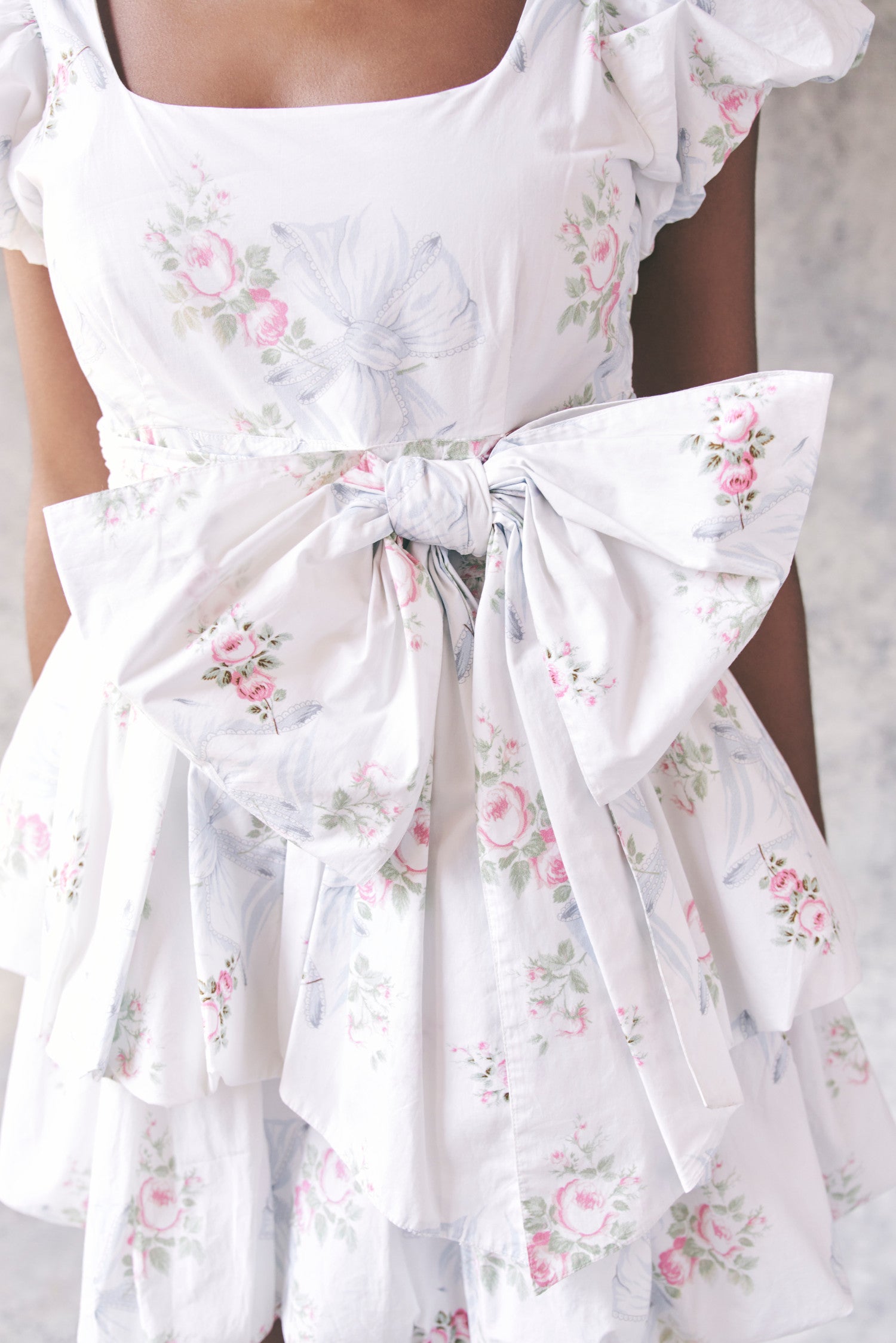Close up image detailing bow and floral print on babydoll mini dress