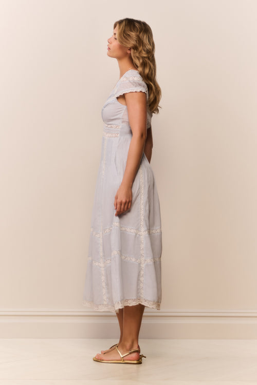 Woman wearing a light blue dress against a plain white wall