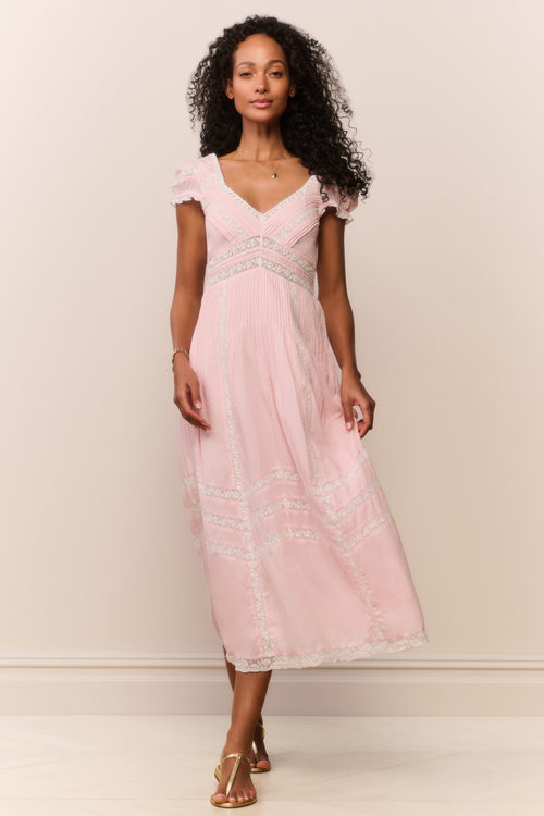 Woman wearing a pink lace dress against a plain background