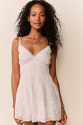 Woman wearing a white lace dress against a plain background