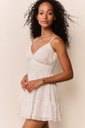 Woman wearing a white lace dress against a plain background