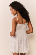 Woman wearing a white lace dress against a plain background