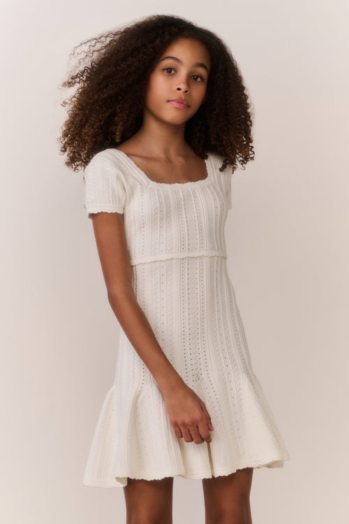 Tween wearing a white dress with a plain background
