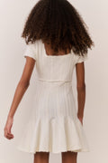 Tween wearing a white dress with a plain background