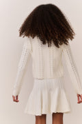 Tween wearing a white knit sweater and matching dress on a plain background