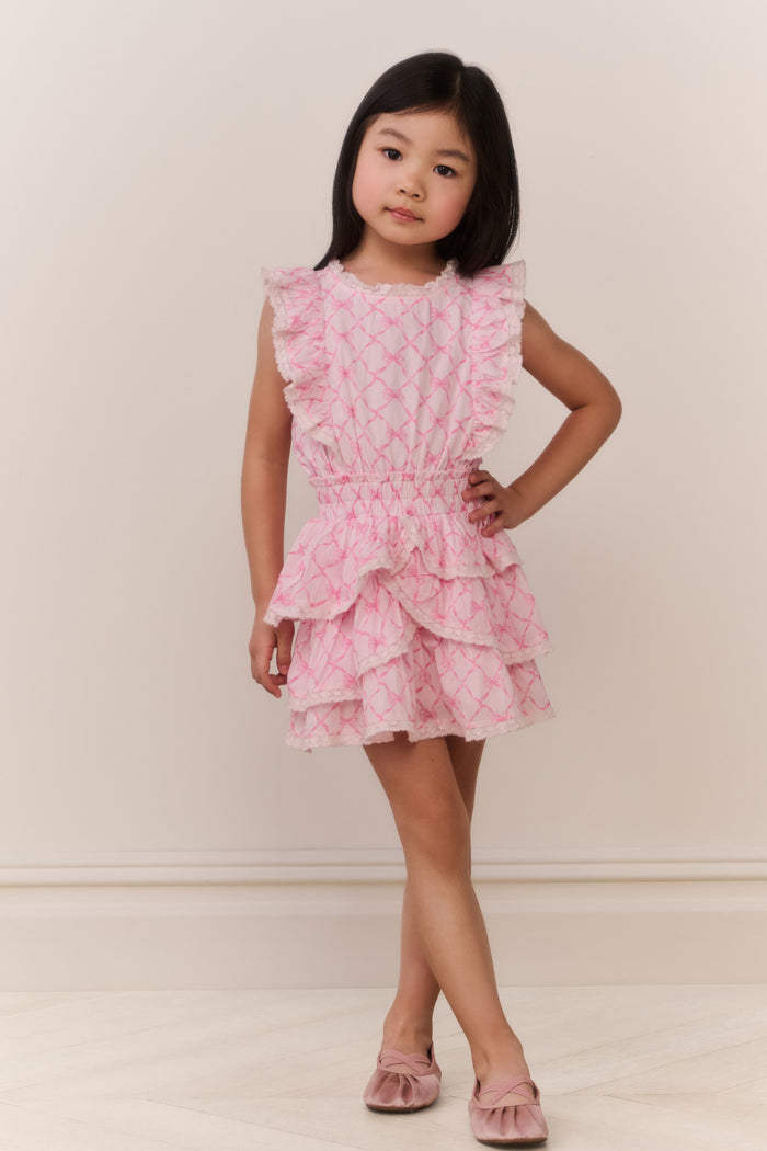 Young girl wearing a pink ruffled dress against a plain background