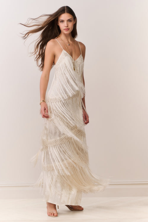 Woman wearing a flowing white dress against a plain background