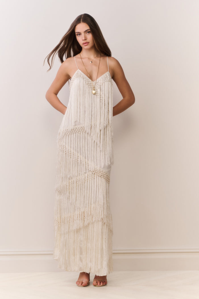 Woman wearing a long, flowing fringe dress on a plain background
