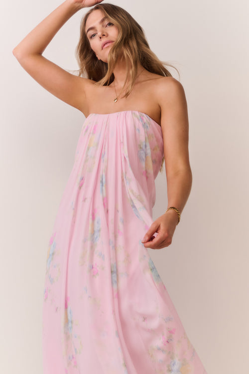 Woman wearing a pink strapless dress with floral patterns on a plain background