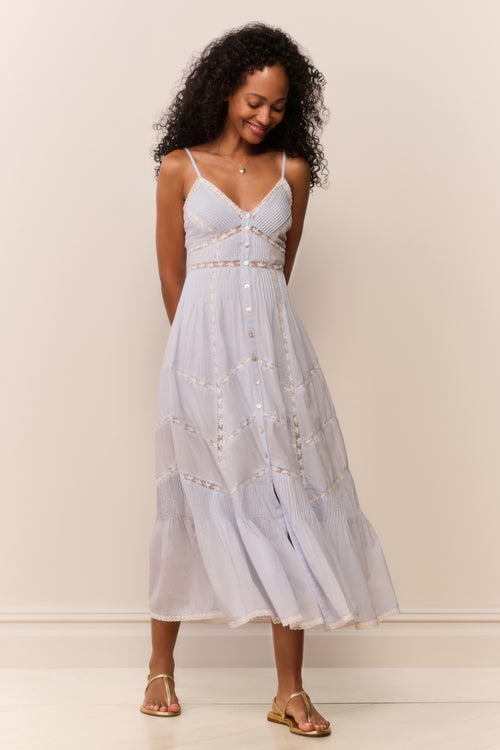 Woman wearing a light blue dress with white polka dots against a plain background