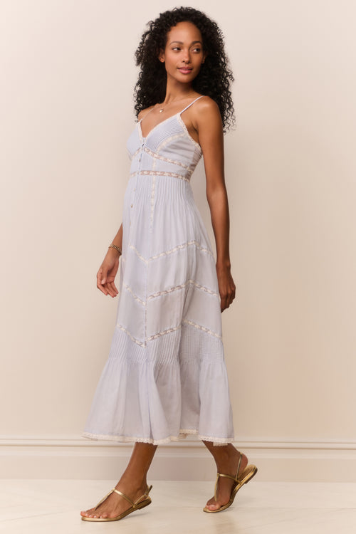 Woman wearing a white dress with thin straps against a plain background