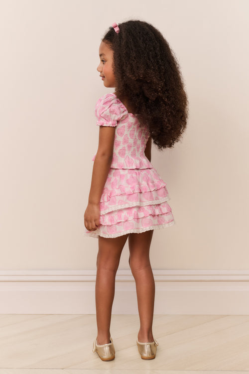 Young girl wearing a pink floral dress with a white background