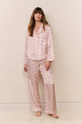 Woman wearing a pink floral pajama set against a plain background