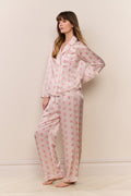 Woman wearing a pink floral pajama set against a plain background