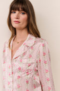 Woman wearing a pink floral pajama set against a plain background