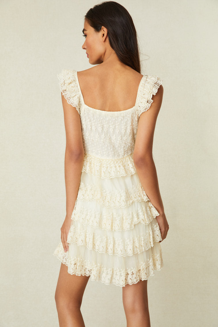 Model is wearing a mini features stunning embroidered mesh with scalloped edges and ruffle detailing all over the straps and the multi-tiered skirt