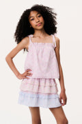 Young girl wearing a pink top and light blue tiered skirt on a white background