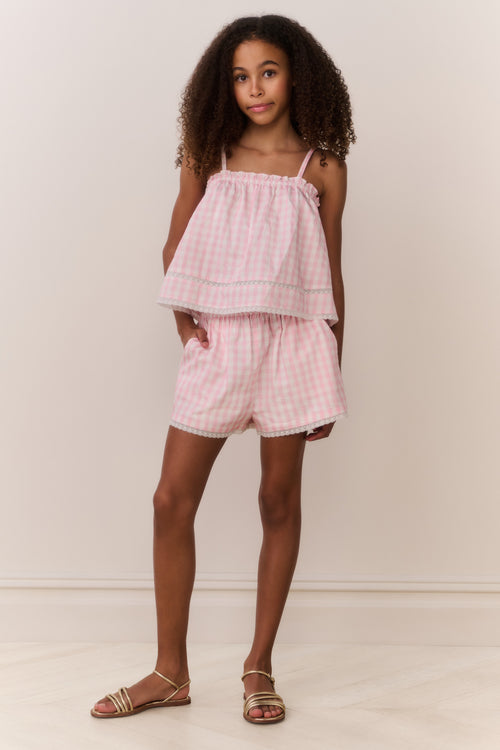 Tween wearing a pink checkered outfit against a plain background