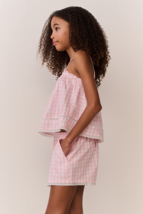 Tween wearing a pink checkered outfit against a plain background
