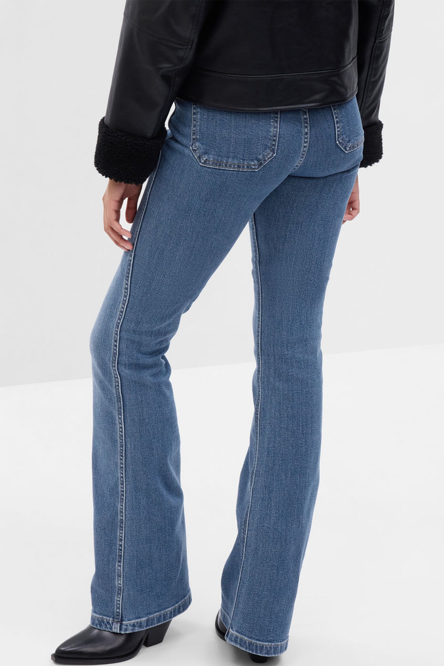 Back image of model wearing blue high rise flare jeans with pockets on back