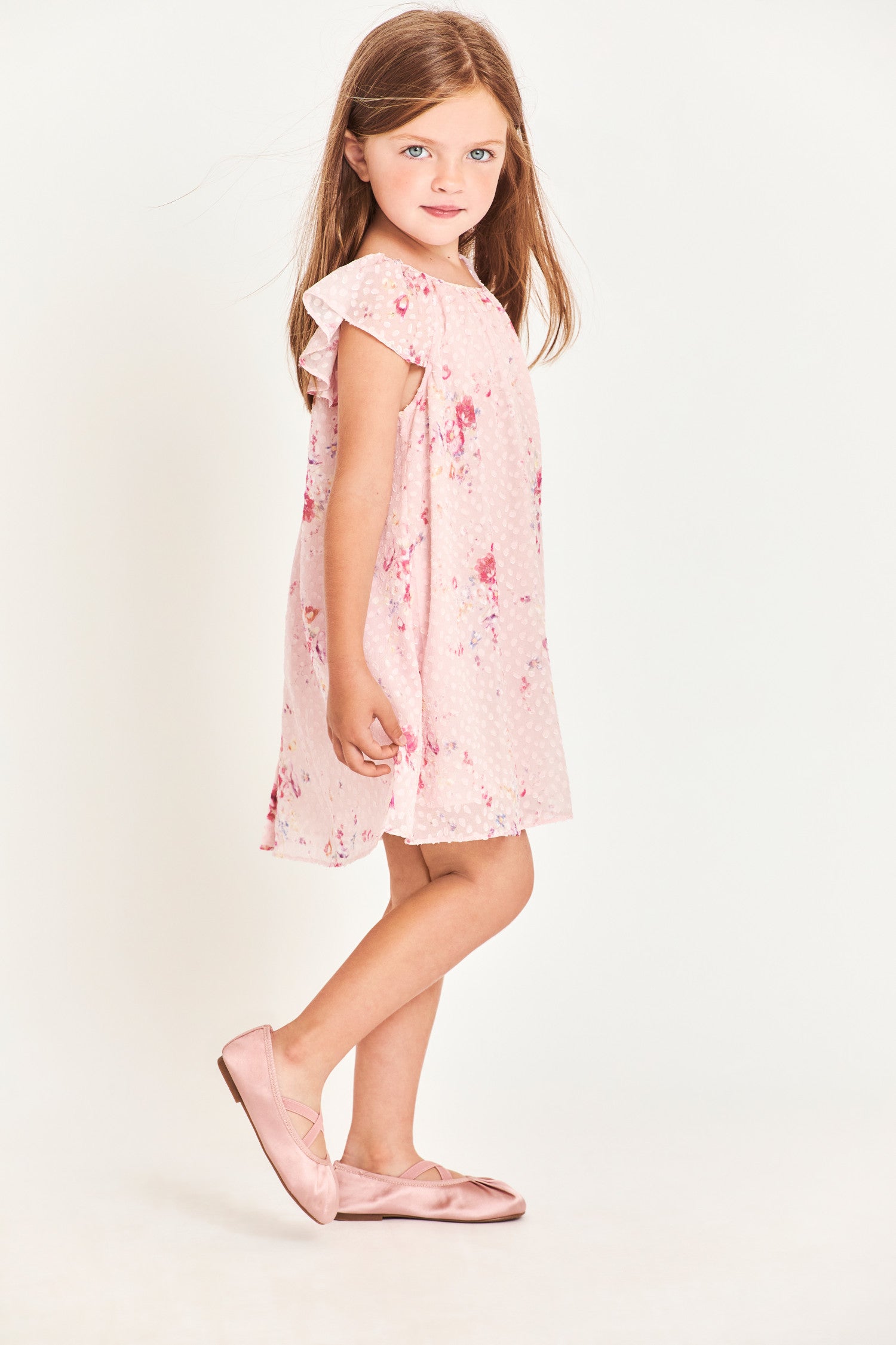 Side image of model wearing kids pink mini dress