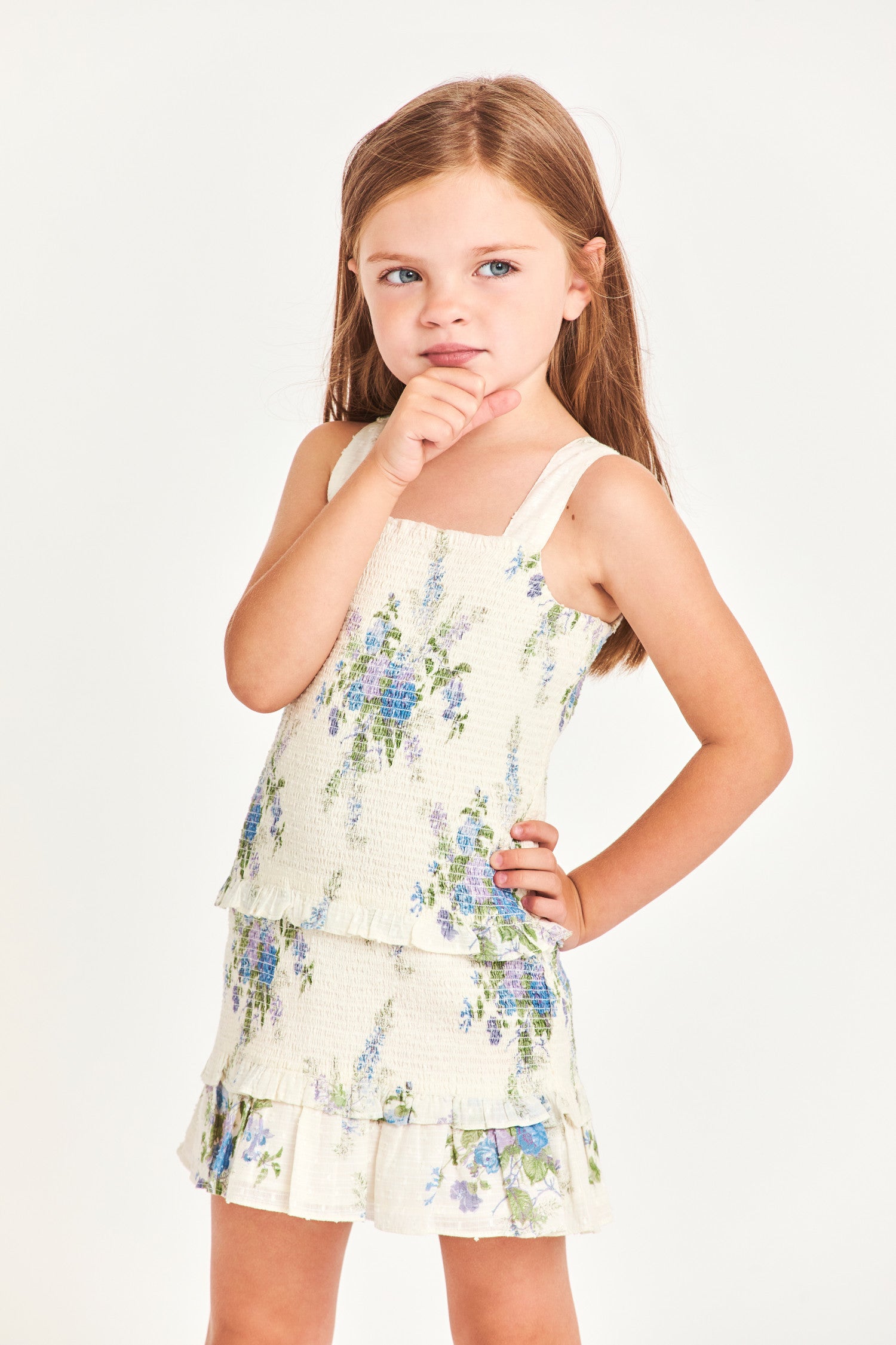 The girl’s Clancey dress is a white 100% cotton dress with blue flower detailing. It features a ruffled two-tier bottom and waistband. 