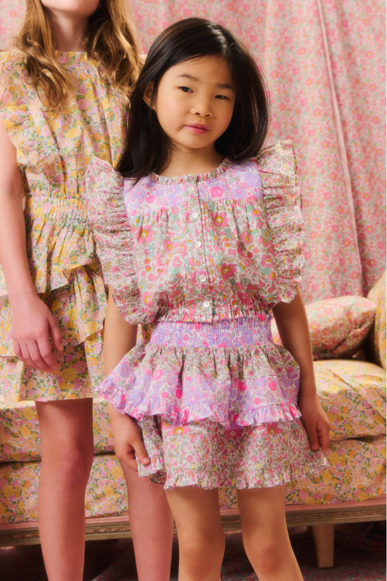 Girls' two-toned floral top with short flutter sleeves, a ruffled high neck, buttons down center front and a fixed waistline at the bottom hem.