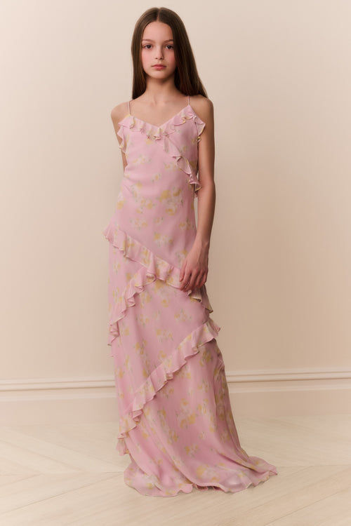 Young girl wearing a pink floral maxi dress against a plain background